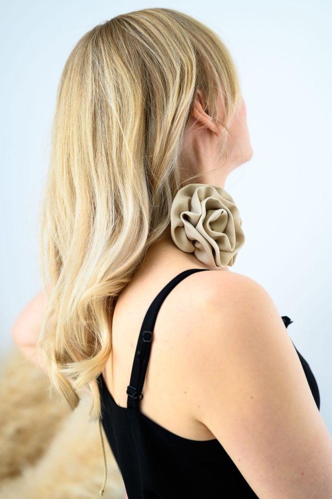 Capsule wardrobe. A woman in black strap top and gold flower accessory on her neck.