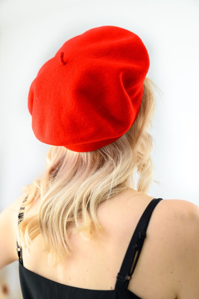 Capsule wardrobe a woman in black strap dress and a red hat